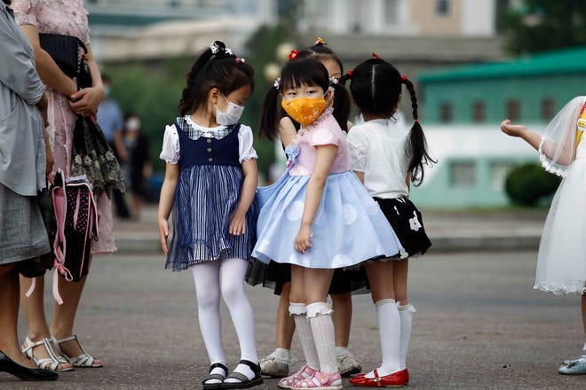 Kindergarten children, wearing face mask, wait for a bus in Pyongyang, Saturday, June 19, 2021.