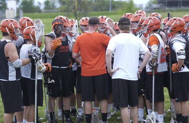 Then-Loveland lacrosse coach Mark Lynch (orange shirt) gathers his Tigers up at a practice.