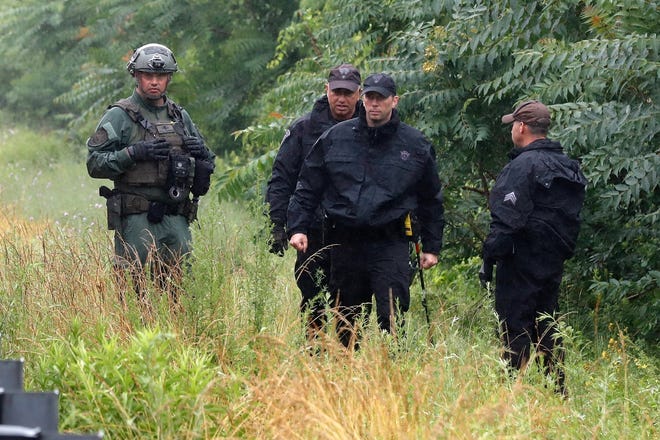 Police work on in the area of an hours long standoff with a group of armed men that partially shut down interstate 95, Saturday, July 3, 2021, in Wakefield, Mass.  Massachusetts state police say nine suspects have been taken into custody.