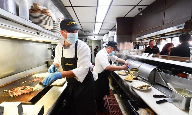 In this photo taken on June 15, 2021 kitchen staff continue wearing facemasks while preparing breakfast at Langer's Delicatessen-Restaurant in Los Angeles, California, on California's first day of fully reopening its economy after some fifteen months of Coronavirus pandemic restrictions. - California state regulators on June 17, 2021 have approved revised workplace pandemic rules ending most mask requirements for employees vaccinated againt the coronavirus.