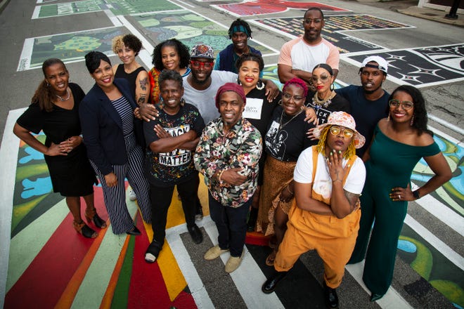 Alandes Powell (far left), of Black Art Speaks, poses with a group of the artists who contributed to the Black Lives Matter mural painted in front of City Hall in downtown Cincinnati last year.