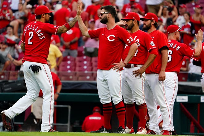 Cincinnati Reds right fielder Nick Castellanos (2) and Cincinnati Reds left fielder Jesse Winker (33) high five at the conclusion of a 10-3 win against the Colorado Rockies, Saturday, June 12, 2021, at Great American Ball Park in Cincinnati. The Cincinnati Reds won, 10-3. 