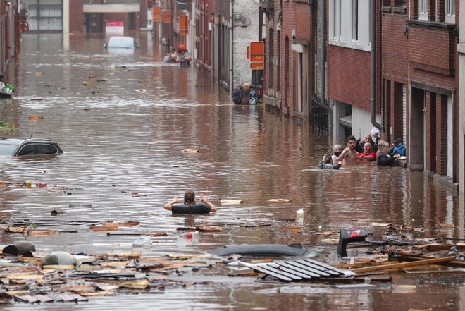 A woman is trying to move in a flooded street following heavy rains in Liege, Belgium on July 15, 2021.