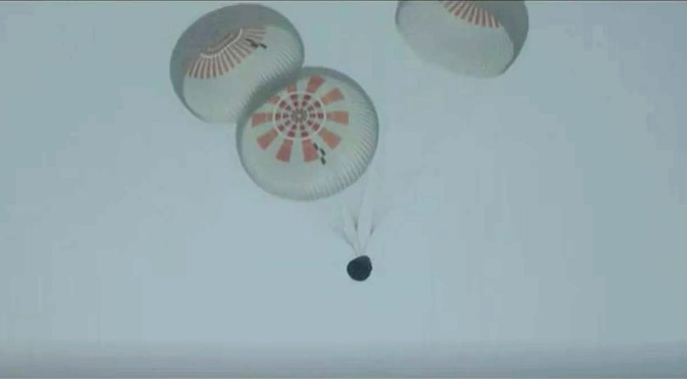 In this image taken from SpaceX video a SpaceX capsule carrying four people parachutes into the Atlantic Ocean off the Florida coast, Saturday, Sept. 18, 2021. The all-amateur crew was the first to circle the world without a professional astronaut.