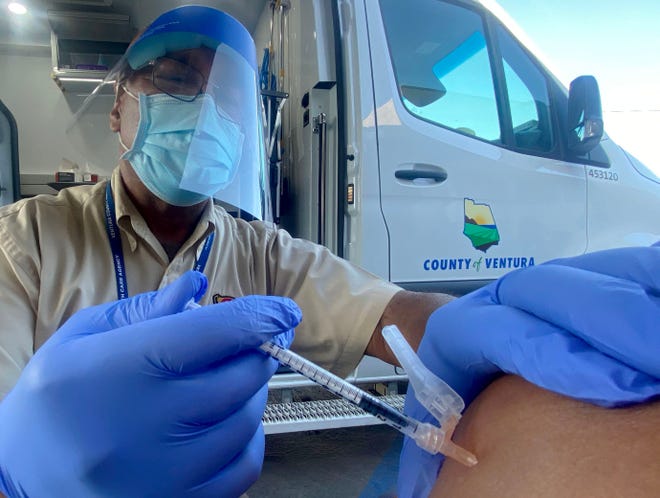 Russell Rawls, a technical specialist for the Ventura County Public Health Department, administers a Pfizer COVID-19 vaccine at a pop-up vaccination clinic on Thursday.