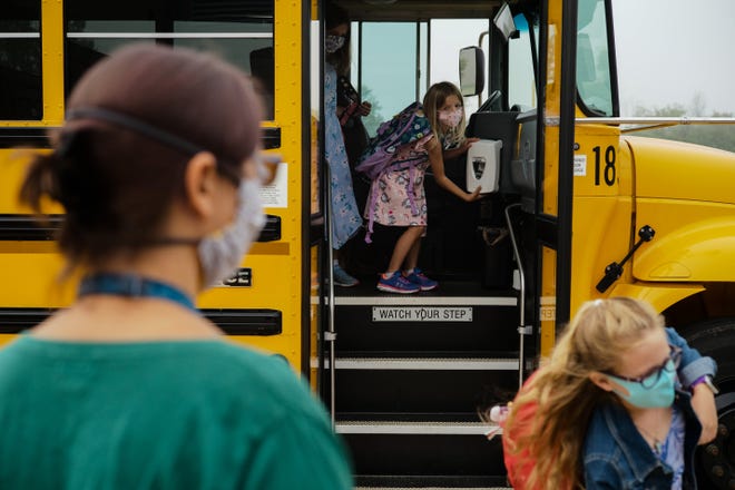 Students get hand sanitizer as they step off the school bus during the first day of school on Tuesday, Sept. 1, 2020 at Heritage Elementary School in Lewis Center, Ohio. The school is part of the Olentangy School District.