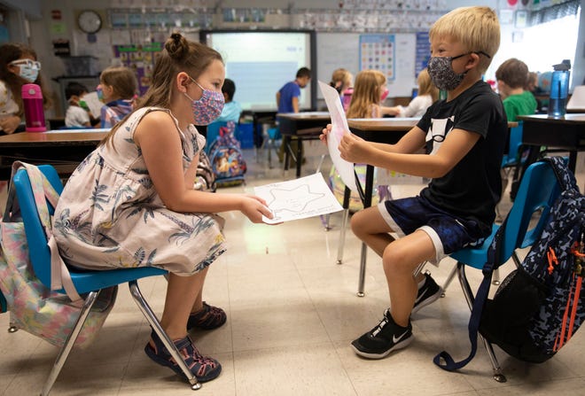 First graders Ella Siciliano, left, and Crosley Roewer share their work during an assignment in Julie Fischer's first-grade class at J.F. Burns Elementary, August 31, 2021. Kings Local Schools has mandated masks for pre-K through sixth grade. As students walk into the classroom, they use hand sanitizer to clean their hands.