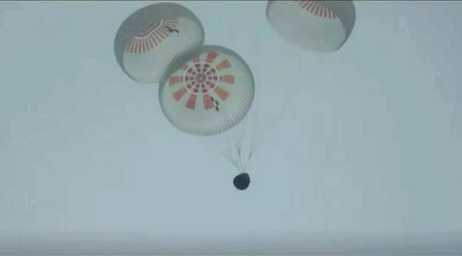 In this image taken from SpaceX video, a SpaceX capsule carrying the Inspiration4 crew parachutes into the Atlantic Ocean off the Florida coast on Saturday night.