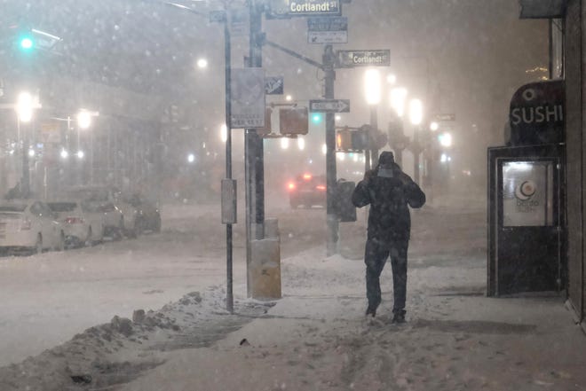 VARIOUS CITIES - JANUARY 29: People walk through lower Manhattan in the pre-dawn hours as a winter storm brings heavy snow, freezing temperatures and blowing winds to the area on January 29, 2022 in New York City.