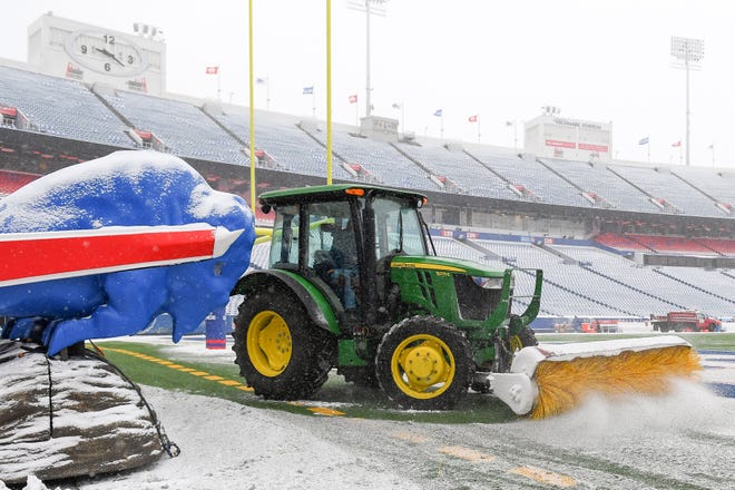 Stadium staff remove snow from the field at Highmark Stadium before a game between the Atlanta Falcons and the Buffalo Bills on Jan. 2 in Orchard Park, N.Y.