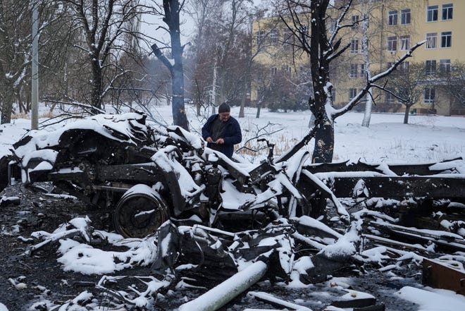 A man takes photos of still smoldering destroyed Russian military vehicles on the outskirts of Kharkiv, Ukraine, Friday, Feb. 25, 2022.